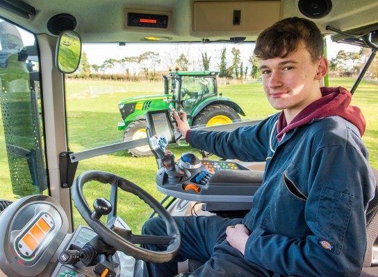 Agriculture Student driving a tractor and using Agri Tech technology