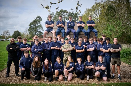 Uniformed Services cohort stood with lecturers, in front of our outdoor obstacle course wall