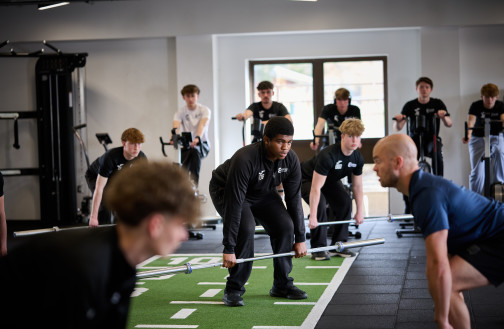 Sports students engaged in a barbell lifting demonstration