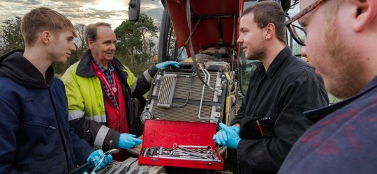 Agriculture Engineering students working on a tractor in the field with their lecturer