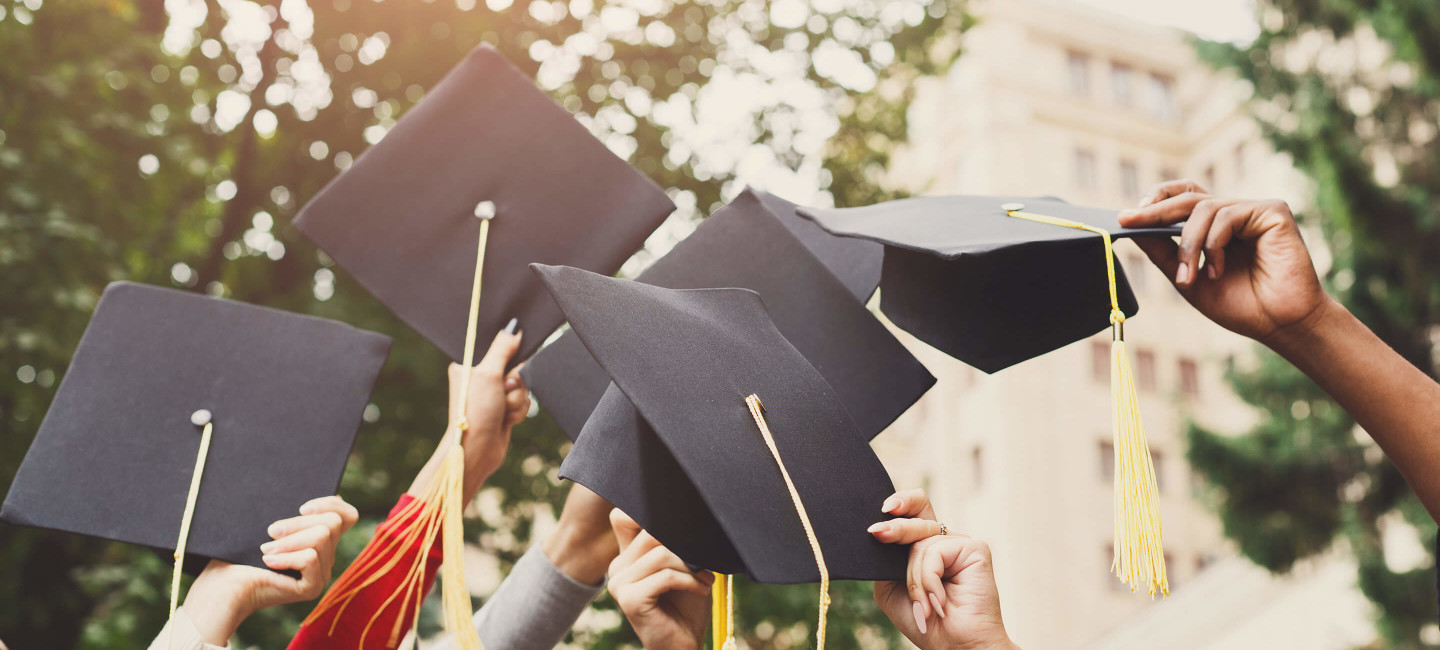 Close-up of students raising caps at graduation