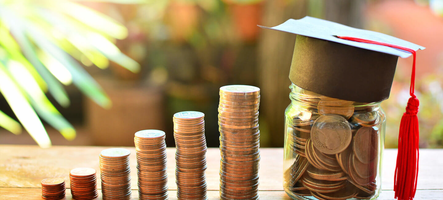 Columns of pennies with jar of pennies wearing graduation cap