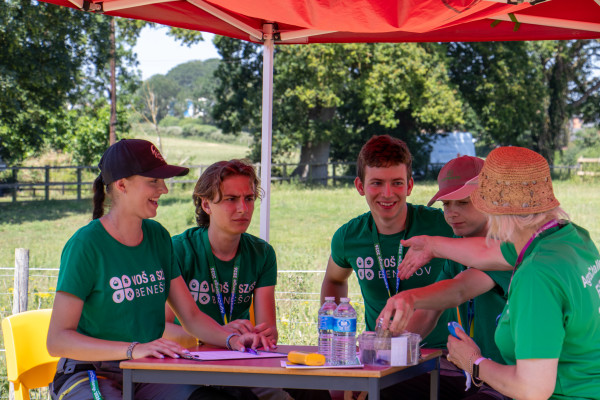 Four students sat at a table with a competition judge looking at the contents of seed containers