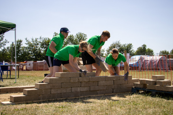 Four students working as a team to build a low brick wall