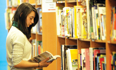 Easton college student looking at a book from the library shelves
